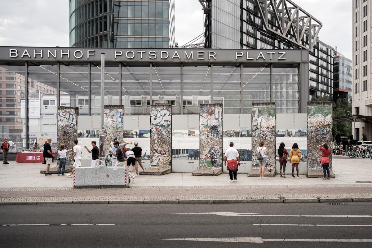 Potsdamer Platz – A berlini fal egykori nyomvonalának helyén itt ma utak, járdák, irodaházak, bevásárlóközpontok állnak. A fal pontos vonala az 1990-es évek nagyszabású városfejlesztése során nagyrészt beépült. A nyomvonalat ma több helyen a földbe süllyesztett kő- vagy fémcsík jelzi – ahogy Berlin más pontjain is. A képen látható falmaradványokat az 1990-es évek végén, a Potsdamer Platz újjáépítése idején, 1998 és 2000 között helyezték el. Ezek eredeti falpanelek, azonban nem az egykori helyükön állnak: a tér újrarendezése során emlékezeti céllal kerültek ide Fotó: Szirbek Anita